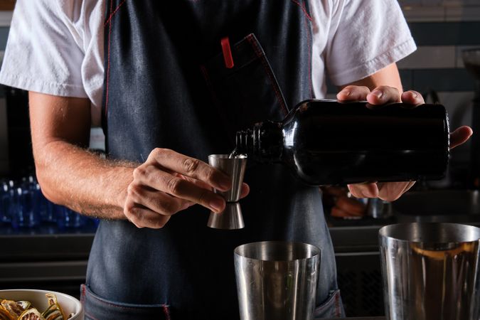 Crop male bartender mixing drink in bar