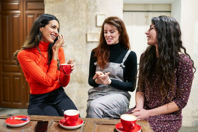 Three women enjoying cappuccinos at cafe