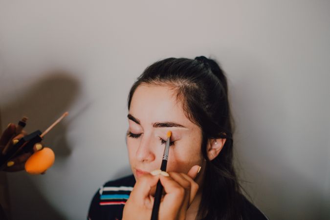 Young woman getting makeup by makeup artist in salon