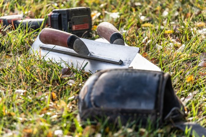 Cement Trowels And Tools On Grass At Construction Site