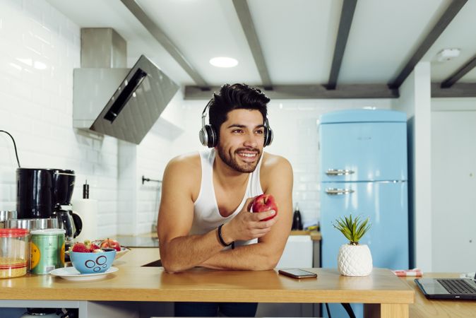 Young happy man in headphones holding apple