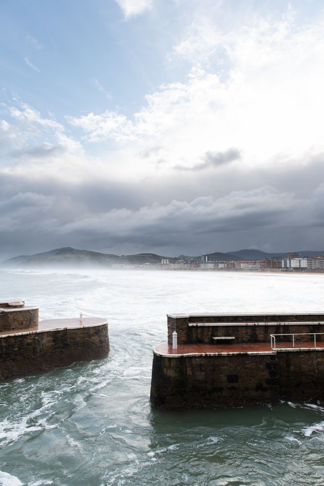 Rock breakwater with raging sea on cloudy weather