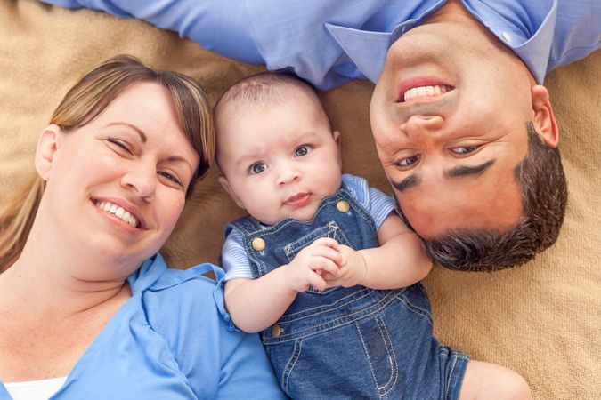 Young Couple Laying With Their Infant On A Blanket