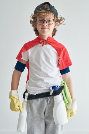 Positive boy wearing costume with detergents standing near studi