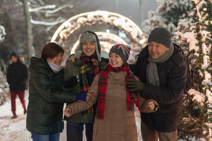 Family in winter outfits standing beside Christmas decoration during nighttime