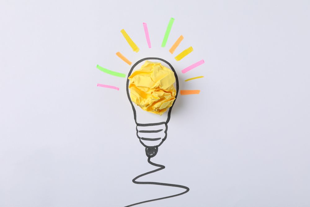 Drawn light bulb and paper ball on light background. Good idea concept