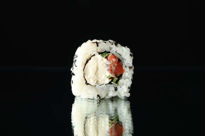 Sushi roll on dark mirror background, close up