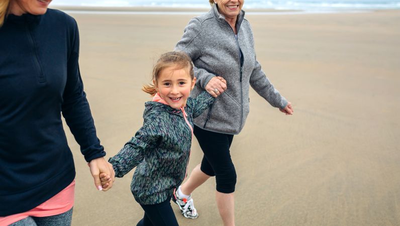 Girl running with two women on the beach