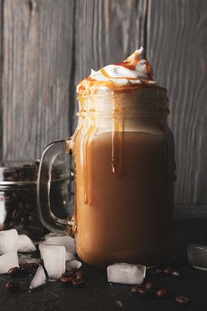 Iced coffee with poured cream on gray wooden background