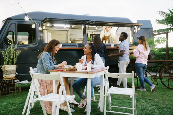 Diverse women having lunch near food trunk