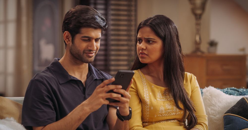 Young Indian Couple Sitting On The Sofa at Home: Woman Annoyed at her Boyfriend for Spending Too Much Time On Smartphone.