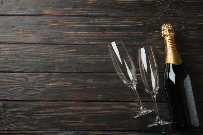 Champagne glasses and bottle on wooden background, space for text
