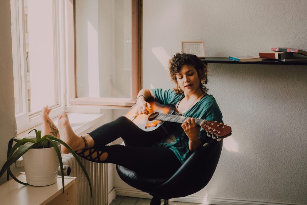 Content woman playing guitar at home