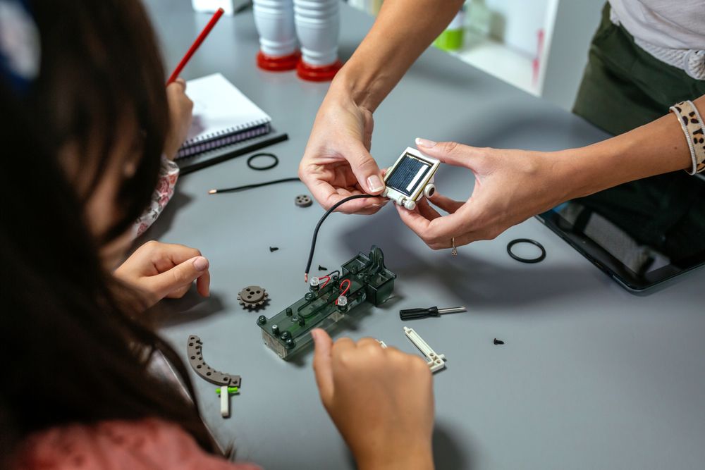 Female teacher explaining to student how connect a solar panel on electrical circuit