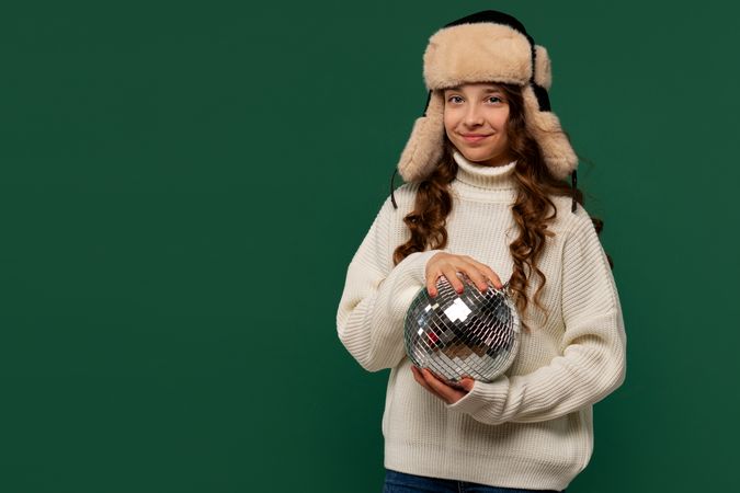 Young girl in fur hat posing with disco ball.