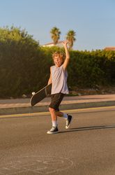 Excited boy with skateboard having fun in city