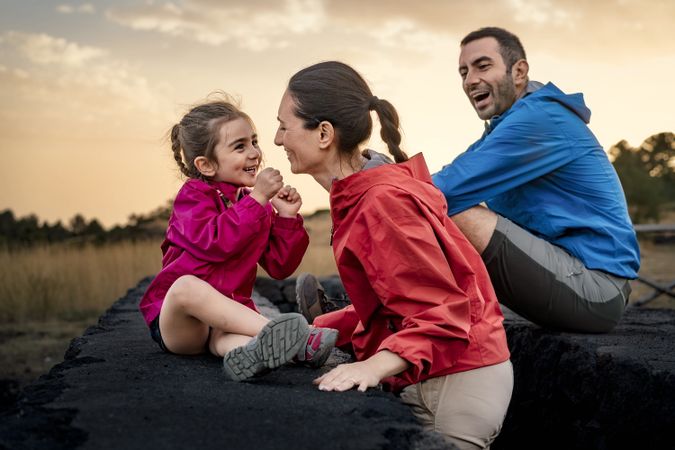 Happy family laughing and playing together in nature at sunset.