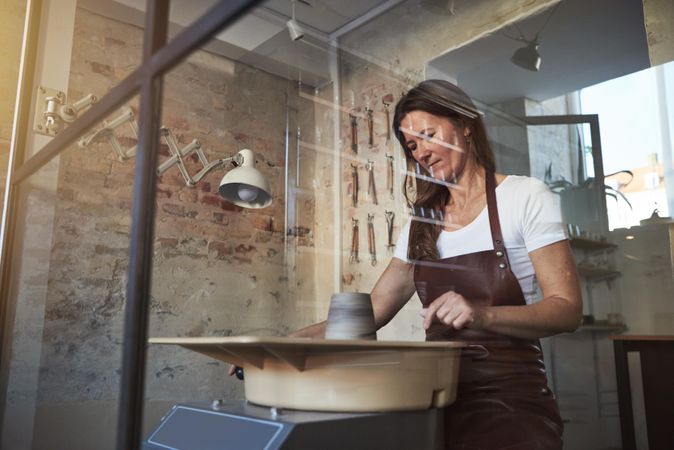 Woman in leather apron at ceramics wheel