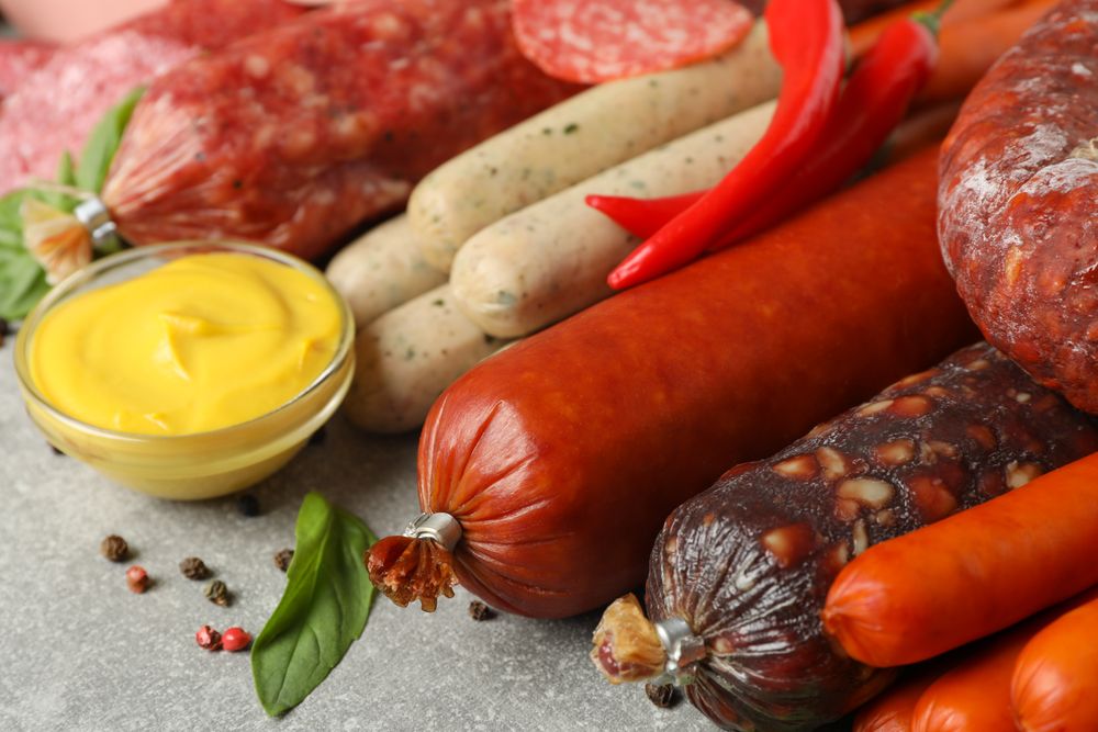 Cured sausages and mustard on grey table
