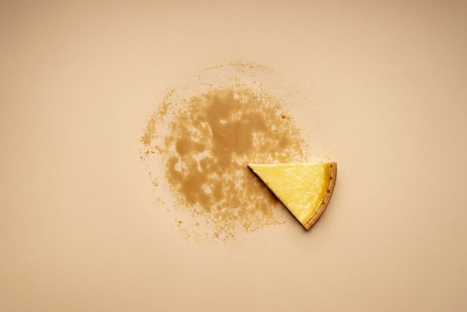 Single piece of cheesecake on a tan background