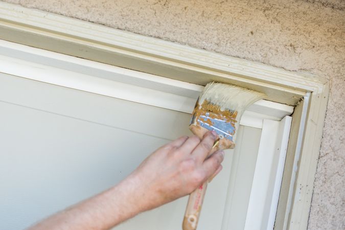 Professional Painter Cutting In With Brush to Paint Garage Door Frame