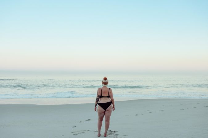 Rearview of an unrecognizable female winter bather standing at the beach in swimwear