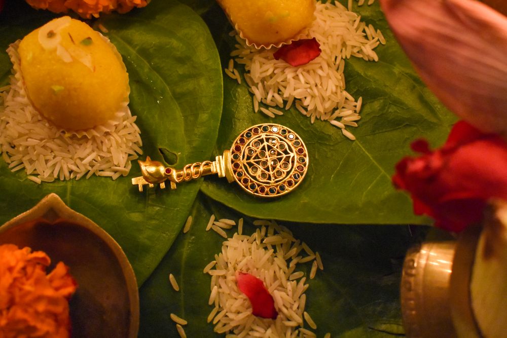 Silver key with mandala head beside yellow ladoo