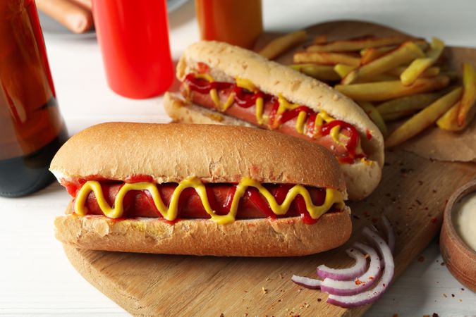 Tasty hot dogs, beer and sauces on wooden background