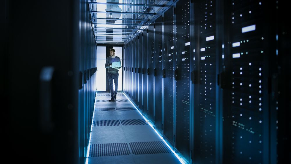 IT Technician Works on Laptop in Big Data Center full of Rack Servers.