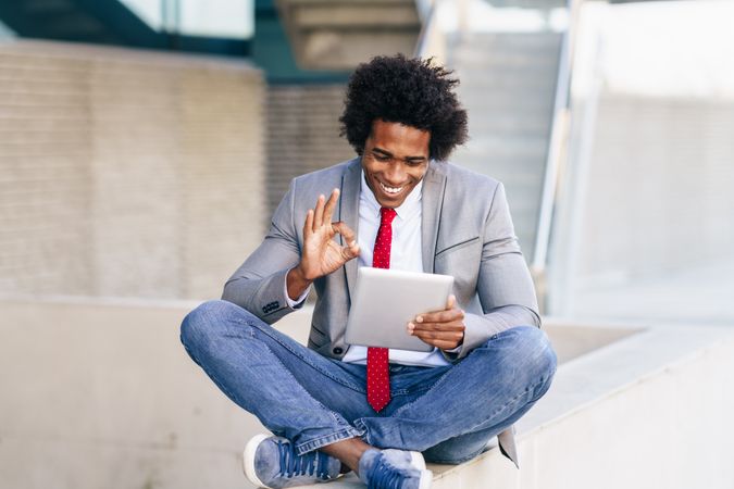Happy man talking at his digital tablet sitting cross legged