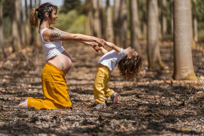 Pregnant mother and little daughter having fun in park