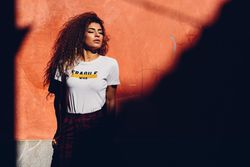 Arab woman with curly hair standing in the sun with her eyes closed