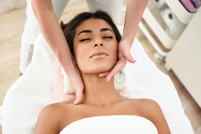 Woman receiving a relaxing facial treatment from a aesthetician