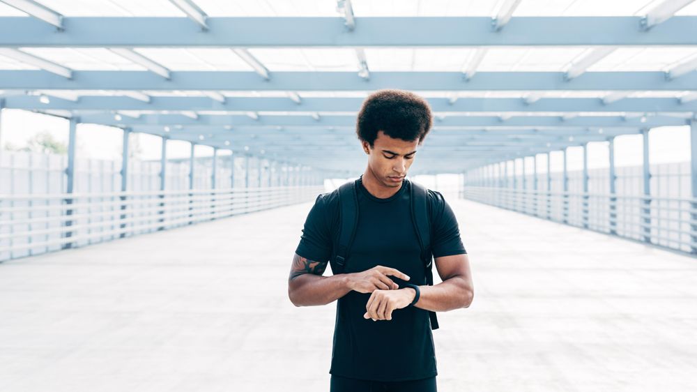 Black man on pedestrian bridge checking watch