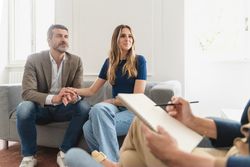A married couple speak with a therapist taking notes