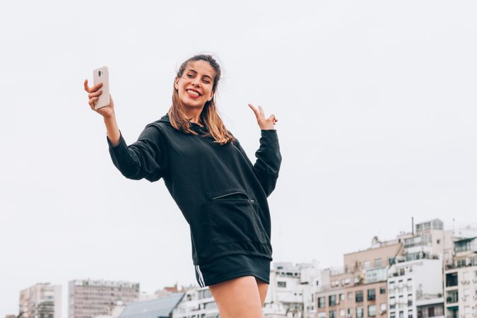 Content young woman in casual wear taking selfie at city street