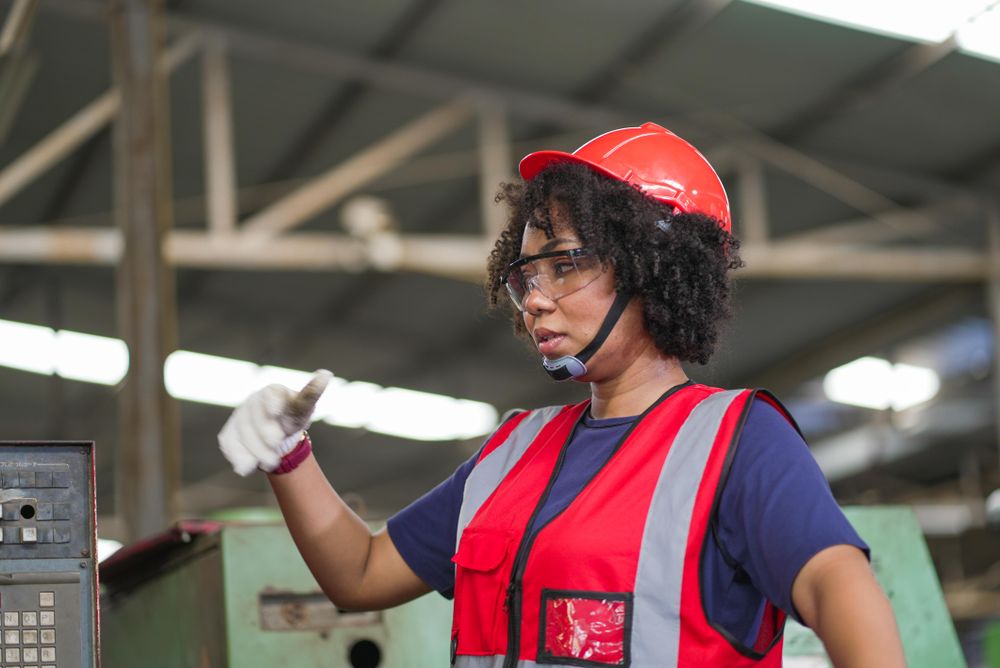 Black female worker talking with colleague standing at factory construction site