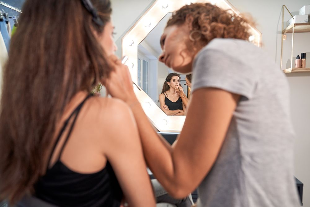 Visagiste applying makeup on woman