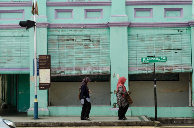 Side view of two women walking on sidewalk in George Town, Penang, Malaysia