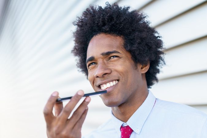 Smiling man taking voice notes on his phone