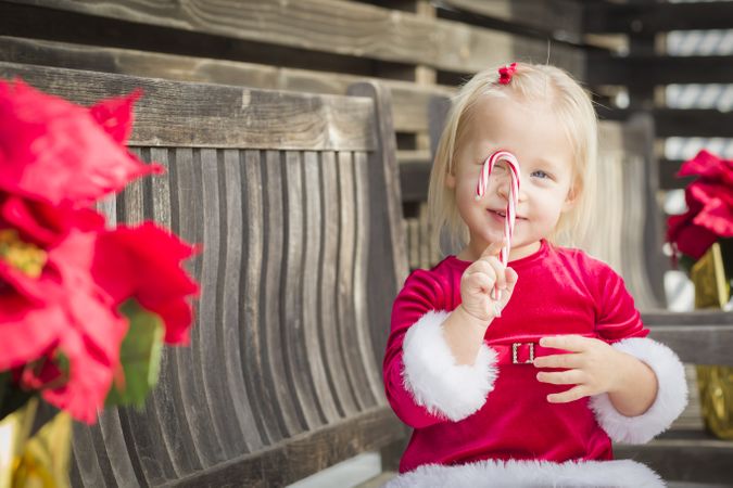 Adorable Little Girl Sitting On Bench with Her Candy Cane