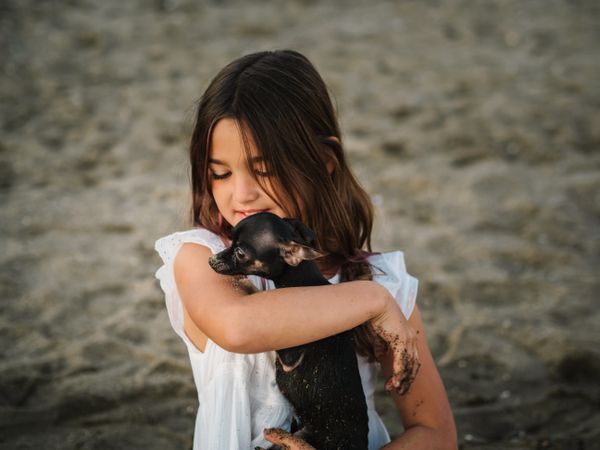Girl with little dog on sandy beach
