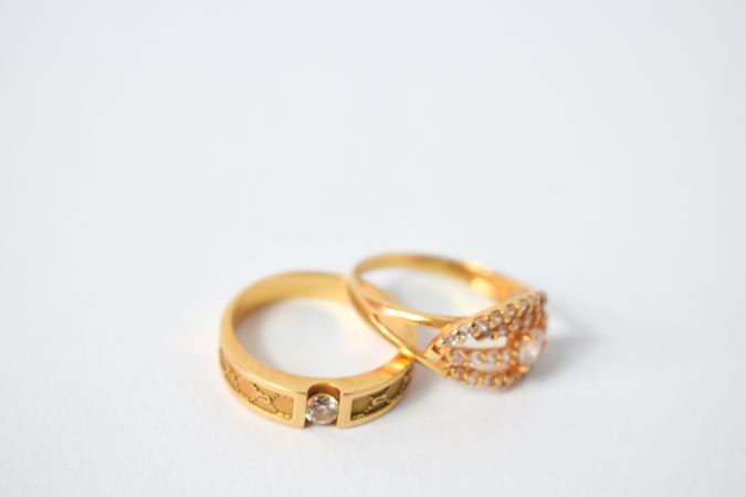 Two gold wedding bands together on plain table