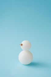 Snowman made of Christmas bauble decoration on pastel blue background