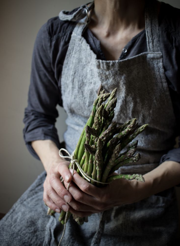 Faceless woman holding bundle of green asparagus