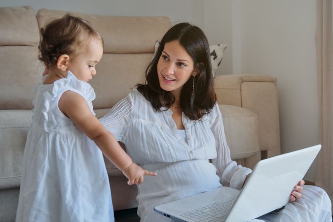 Mom with toddler working on laptop from home