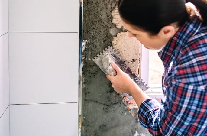 Female bricklayer leveling cement with a trowel