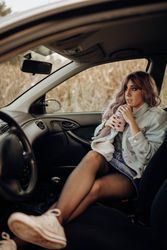 Stylish woman having drink in car