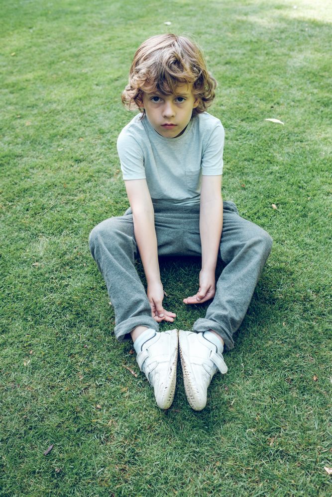Cute boy sitting on grassy meadow