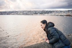 Woman on vacation in warm wear delighting in sunset on seashore